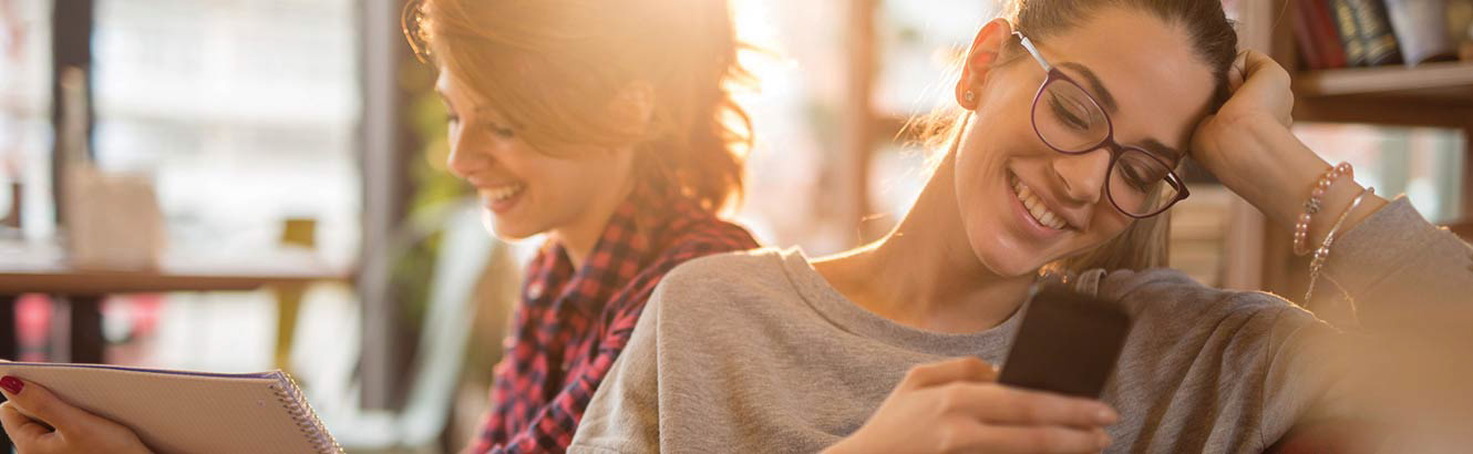 mujer sonriente viendo su teléfono móvil